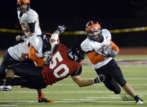 Mansfield's Jonathan Keller (50) attempts to block Princeton's Kevin Ma, right, on Saturday. The game marks the first time that Mansfield has held an official night football game since 1892 when Mansfield staged the first-ever night football game.