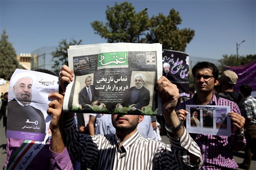 A supporter of Iranian President Hassan Rouhani holds a local newspaper with a headline that reads, "historic call from a return flight," as Rouhani arrives near the Mehrabad airport in Tehran, Iran, today. Iranians from across the political spectrum hailed the historic phone conversation between President Barack Obama and Rouhani, reflecting wide support for an initiative that has the backing of both reformists and the country's conservative clerical leadership.