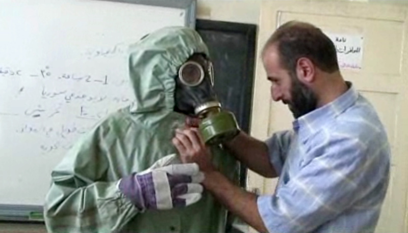 A volunteer adjusts a gas mask and protective suit on a student during a classroom session on how to respond to a chemical weapons attack in Aleppo, Syria. The drills came amid continued diplomatic wrangling over how to collect Syria's arsenal of chemical and biological agents.