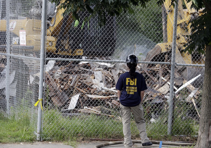 In this Aug. 7, 2013 file photo, an FBI agent watches as the Cleveland home of Ariel Castro, where three women were held captive and raped for more than a decade, was demolished. Castro, 53, now serving a life sentence for the kidnapping and rapes, was found hanging in his cell, Tuesday night, Sept. 3, 2013, at the Correctional Reception Center in Orient, Ohio. (AP Photo/Tony Dejak, File)