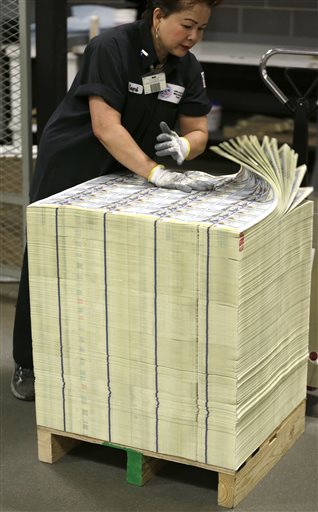 A stack of uncut sheets of $100 bills are inspected before being moved during the printing process at the Bureau of Engraving and Printing Western Currency Facility in Fort Worth, Texas.