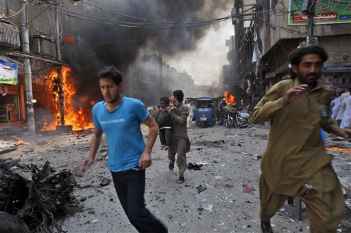 Pakistani run away from the site of a blast shortly after a car explosion in Peshawar, Pakistan, Sunday, Sept. 29, 2013. A car bomb exploded on a crowded street in northwestern Pakistan Sunday, killing scores of people in the third blast to hit the troubled city of Peshawar in a week, officials said.