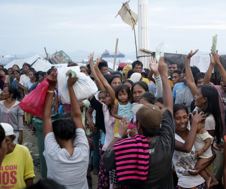 Villagers who fled the fighting between government forces and Muslim rebels cheer a fellow evacuee who just got her bag of relief supplies Wednesday in Zamboanga city in southern Philippines.