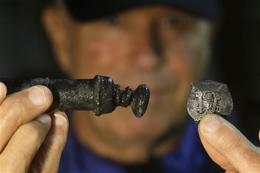 Underseas explorer Barry Clifford holds a piece of eight, right, and a metal syringe salvaged from the wreck of pirate ship Whydah in Brewster, Mass., recently. Clifford discovered the wreck in 1984 in waters off Cape Cod.