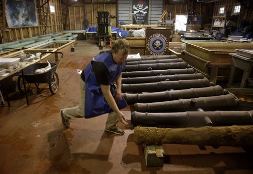 Chris Macort, a field archaeologist working with the Whydah pirate ship museum, reaches down to check one of the ship's cannons at the museum's warehouse in Brewster, Mass. The Whydah sank in a brutal storm in 1717 with plunder from 50 ships.