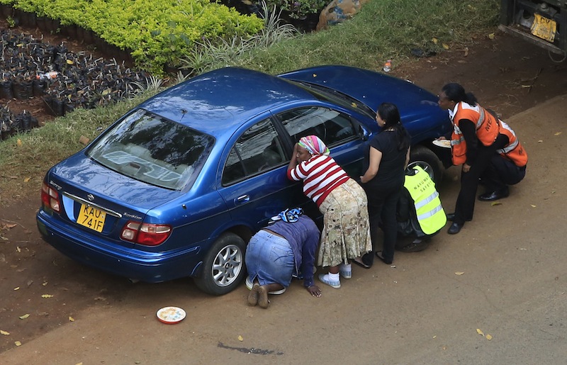 People take cover behind a car along a road during heavy gunfire at Westgate shopping centre in Nairobi September 23, 2013. A day after a Twitter post linked Maine to Saturday's terrorist attack in a mall in Nairobi, Kenya, law enforcement officials refused to say whether they are investigating the possibility that radical Islamist groups are trying to recruit new members in the state. (REUTERS/Noor Khamis) :rel:d:bm:GM1E99N1S4001
