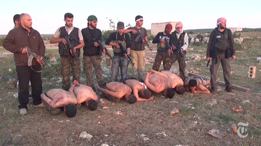 In this screen capture from a video on the New York Times website that was posted on Thursday, Syrian rebel fighters stand over seven Syrian government soldiers with guns near Idlib, Syria in April 2012. The rebel fighters, under orders from commander Abdul Samad Issa, at right, allegedly shot the captured soldiers and put their bodies into a mass grave.
