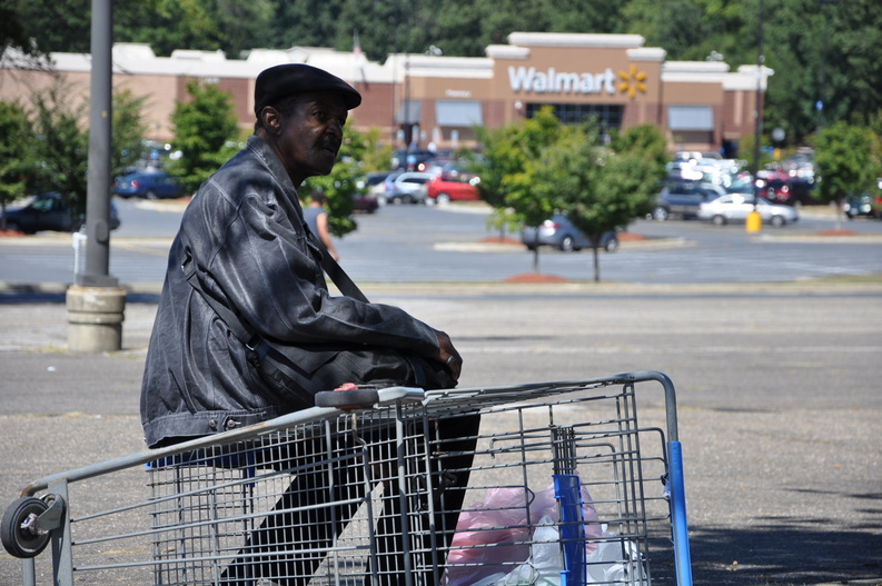 Washington resident Jimmy Pegues, 64, rests on an overturned shopping cart recently after crossing the parking lot of the Walmart store in Landover, Md. The round-trip bus trip from his apartment takes half a day, but Pegues said it is worth it, saving him roughly $110 a month on heart medications and blood thinners through Walmart's $4 generic prescription drug program. Jimmy Pegues Wal-Mart