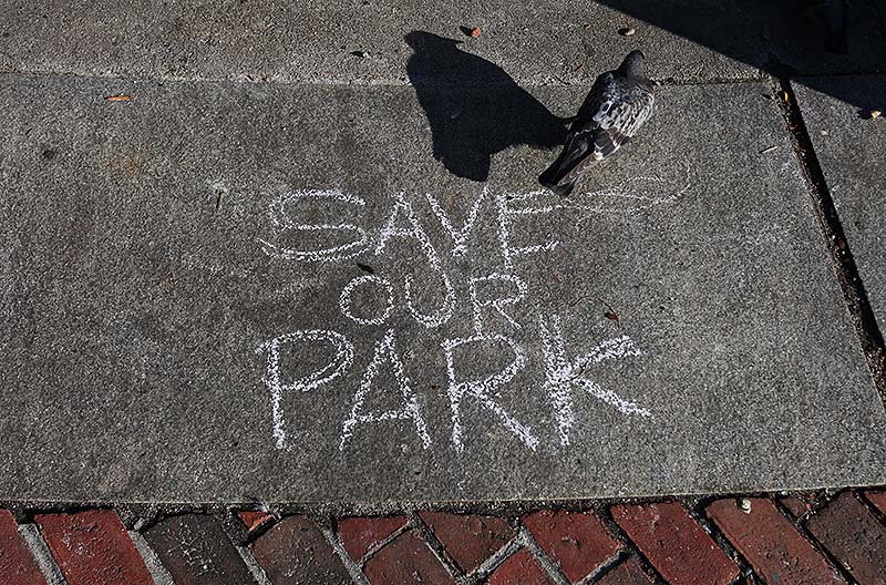 A pigeon walks past a message written in chalk protesting the sale of part of Congress Square Plaza.