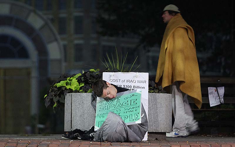 Protester "Ares" of Portland, sleeps on the sidewalk in front of Congress Square Plaza before sunrise Saturday in Portland. "Ares" vowed to stay in the plaza through the weekend to protest the sale of the public space.