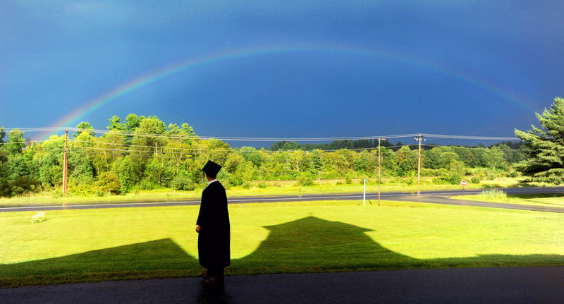 Cody Buzzell, 17, stands in the shadow of Moody Chapel as a rainbow shines over the Maine Academy of Natural Sciences during the charter school’s first commencement event, held last month at the former Good Will-Hinckley School campus in Fairfield.