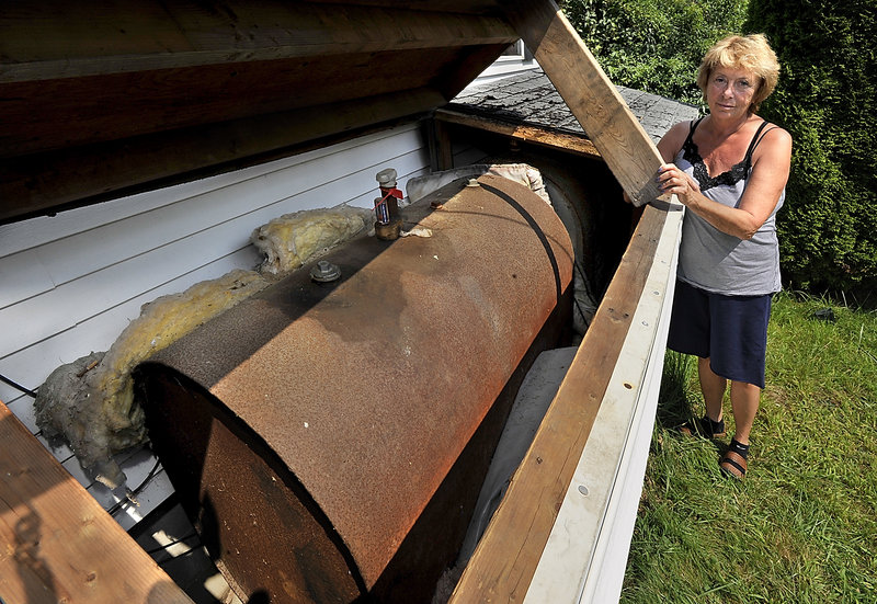 Jo Brillant shows one of the aging oil tanks on her West Bath property that will have to be replaced. The costs of upgrades, combined with an expensive cleanup at another home on her property, climbed to almost $45,000.