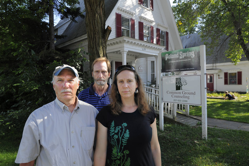 Fryeburg residents Bruce Taylor, left, an intervenor in the case, stands with contract opponents Cliff Hall and Nickie Sekera in front of the Poland Spring offices on Main Street in Fryeburg.