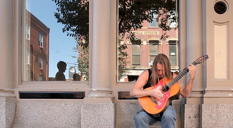 Rick Marr plays a reggae song on his guitar he calls Nikki on Exchange Street in Portland on Aug. 16.