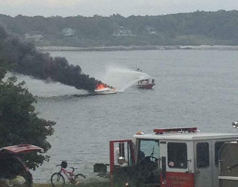A boat burns in Portland Harbor on Sunday afternoon. Four people and a dog were rescued.