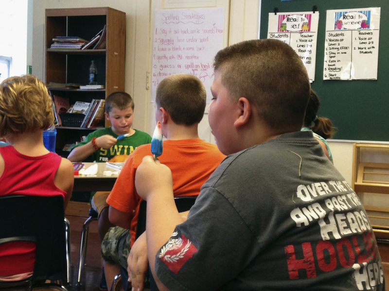 Fourth-graders eat popsicles to stay cool as their teacher reads to them on a hot day in a Monticello, Ill., classroom last week.