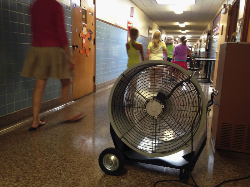 A teacher and students at Washington Elementary School in Monticello, Ill., walk past a large fan last week. The school, built in 1894, has air conditioning in only a few spots and has been sending students home early due to a heat wave.