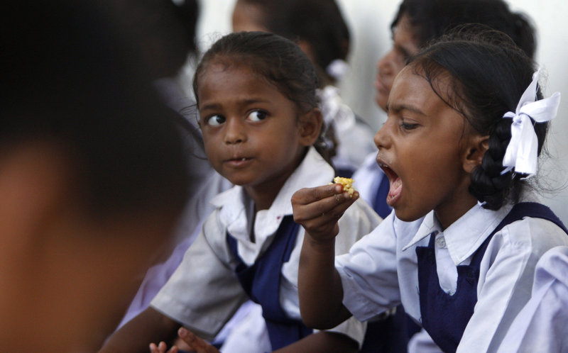 An Indian girl eats a free midday meal at a government school last month. The government will give free food to kids under 6 years old as part of a recently authorized program.