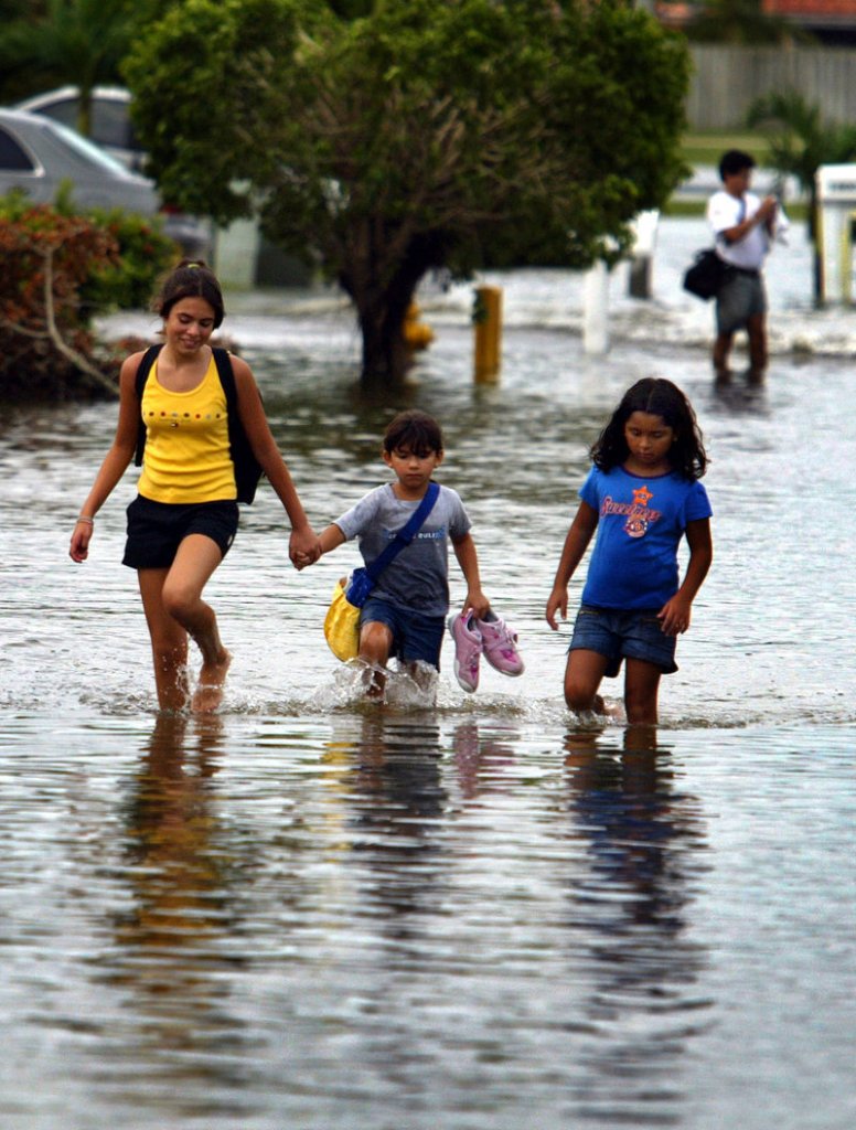 Two school-age children are led down a flooded street in Dade County, Fla., after Katrina brushed by in 2005. Many school districts still lack emergency plans for schools that would help authorities safeguard students.