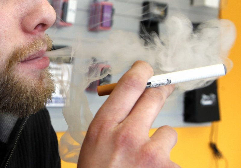 A sales associate demonstrates use of an electronic cigarette and the resulting smoke-like vapor in Colorado. The U.S. government does not regulate e-cigarettes.