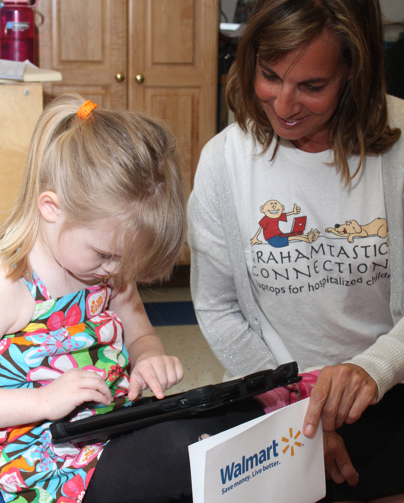 Kilee Graffam, 4, shows Leslie Morissette how she uses one of the iPads donated to Waban by the Grahamtastic Connection.