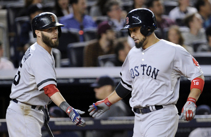 Shane Victorino of the Boston Red Sox, right, is welcomed by Dustin Pedroia after scoring in the fifth inning Thursday night. Boston went on to defeat the New York Yankees 9-8 in 10 innings.