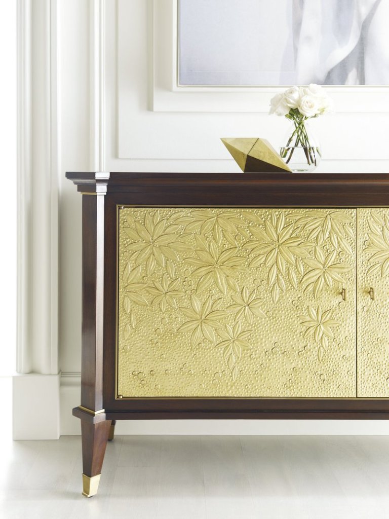 The doors of Baker Furniture's St. Honore Chest have a detailed design and gold finish that add drama.