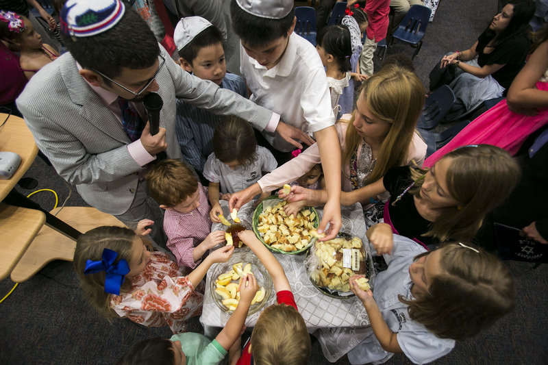 Rabbi Joshua Hearshen blesses children dipping apples into honey Wednesday during the Erev Rosh Hashana, the eve of the Jewish New Year service, at Congregation Rodeph Sholom in St. Petersburg, Fla. Dipping apples into honey is a tradition to bring a sweet new year.