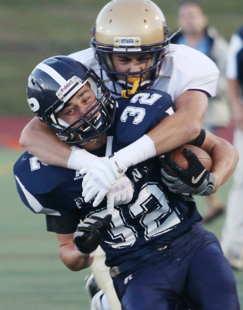 Sam Cross of Cheverus has a firm hold on Justin Zukowski of Portland during Cheverus’ 35-25 victory Friday in an opener at Fitzpatrick Stadium.