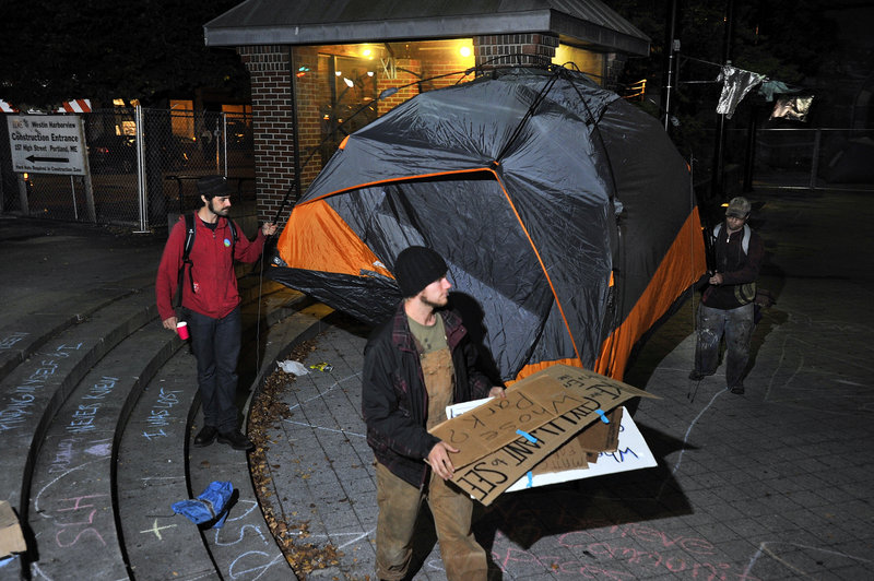 Protesters remove their tent from Congress Square Plaza Friday night after they decided to vacate the area under police orders.