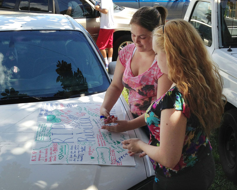 Summer Howard and Alecia Wilkins make a poster Tuesday for Howard’s sister Rebecca Sedwick, 12, who jumped to her death Monday from a concrete plant’s tower in Lakeland, Fla.