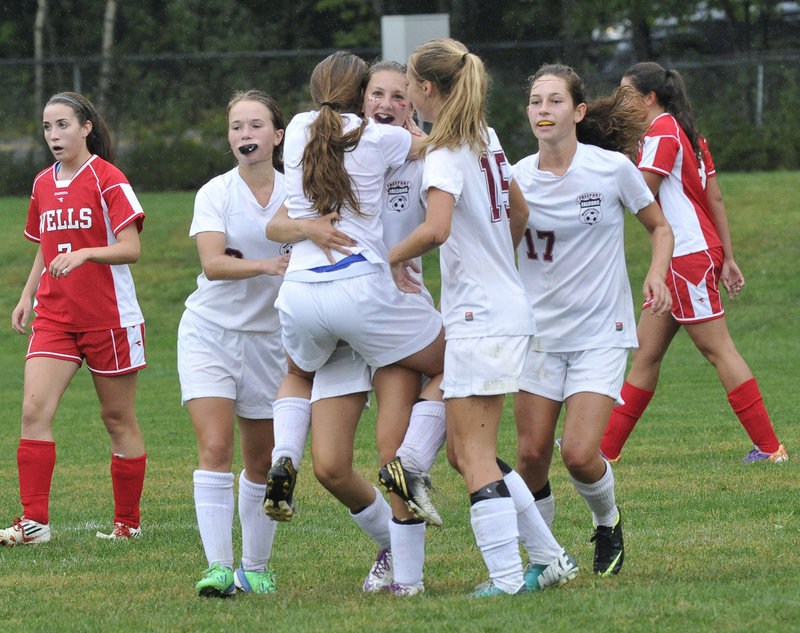 Brooke Heathco, center, gets a hug from Freeport teammate Alyssa Richardson after scoring the first goal in the Falcons’ 2-1 win Friday over Wells.