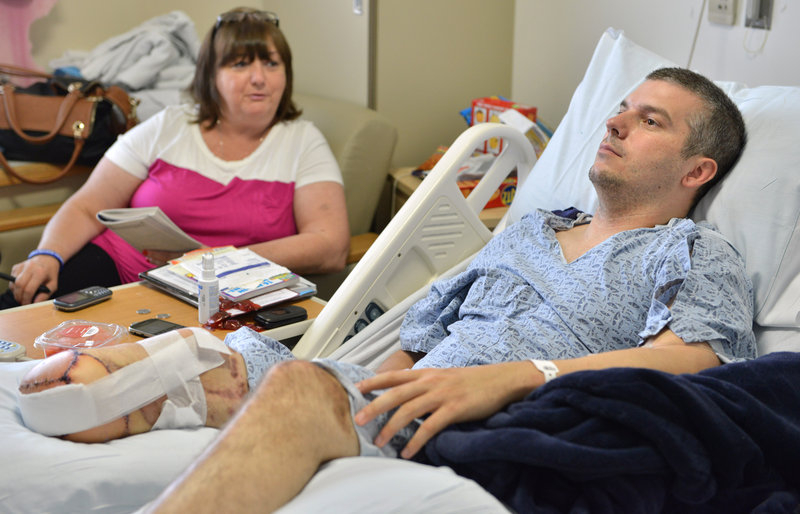 J.P. Norden of Stoneham, Mass., watches TV in the hospital with his mother, Liz Norden. He received $1.2 million from the One Fund after losing much of his right leg in the Boston Marathon attack, but his bills will exceed that.