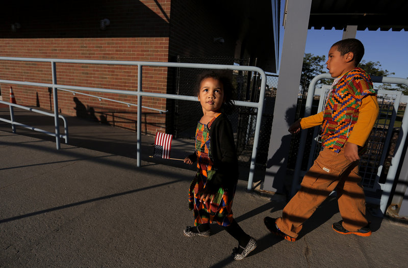 Afia Amoakohene, 3, of Sanford, left, carries an American flag and her brother, Lamar, 7, walks down the ramp at Ocean Gateway after their father Kofi Amoakohene, originally of Ghana, became a U.S. Citizen during a Naturalization Ceremony on Tuesday, September 17, 2013.