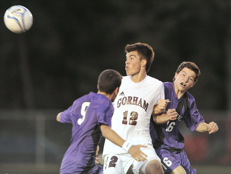 Corey Nadeau of Gorham heads the ball away from Ahmed Adnan, left, and Isaac Santerre of Deering during an early-season game between undefeated SMAA boys’ soccer teams Tuesday night. Gorham pressured for much of the game but Deering’s early goal stood up for a 1-0 win.