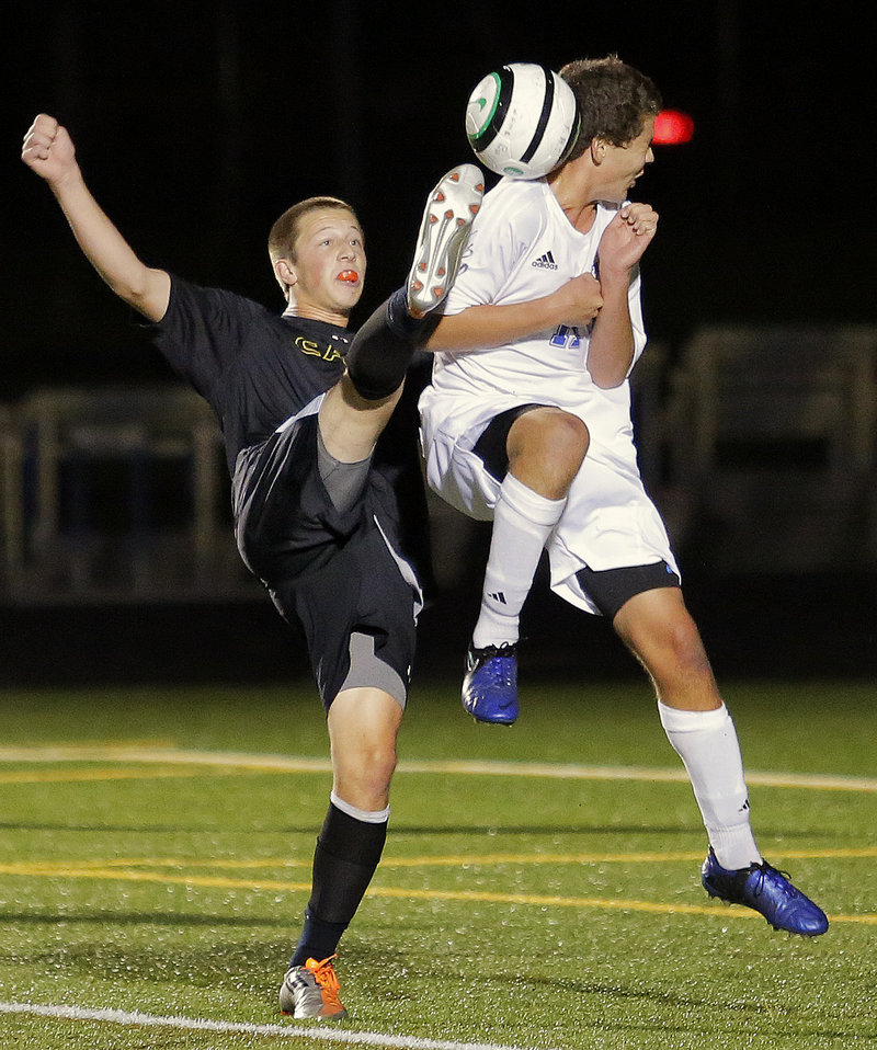 Cole Caswell of Cape Elizabeth, left, goes a bit high for the ball as Falmouth’s Jonah Spiegel awaits the contact during the first half of a scoreless tie Wednesday night in Falmouth.