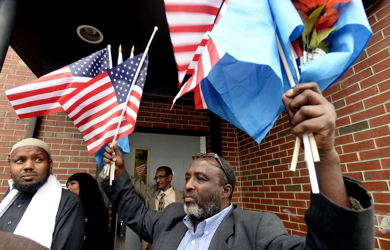 Mohamud Barre, Executive Director of the Somali Culture and Development Association of Maine, holds American and Somalian flags as members of the local Somali community speak with the press after a meeting with Congresswoman Chellie Pingree at the Islamic Society of Portland on Tuesday, Sept. 24, 2013.