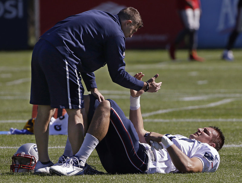 Rob Gronkowski gets a hand from a trainer during a stretching drill before practice Wednesday at Foxborough, Mass. Gronkowski is getting closer to returning.