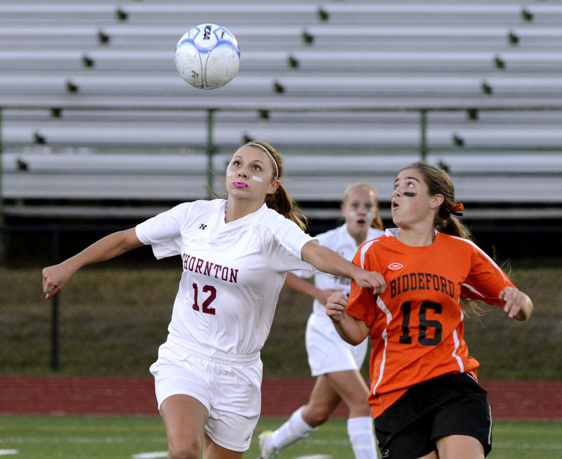 Amanda Arnold of Thornton Academy sets up for a header Wednesday night while holding off Maddy Cantara of Biddeford during their schoolgirl soccer game. Arnold had two assists and a goal in a 3-1 victory for the Golden Trojans.