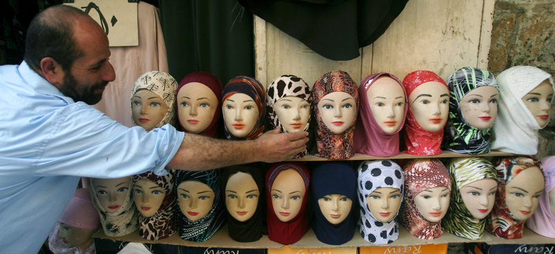 A Palestinian vendor adjusts a mannequin’s head scarf outside his shop in the Old City of Jerusalem, during the Muslim holy month of Ramadan in this September 2007 photo. An expert notes that Americans stereotype women who wear such head scarves.