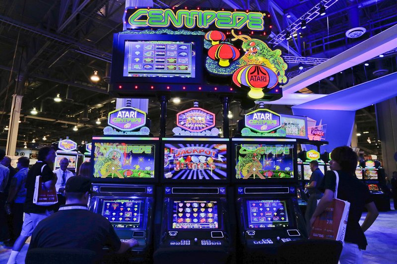 Gaming industry representatives play the Centipede video game slot machine at the Global Gaming Expo Wednesday in Las Vegas.