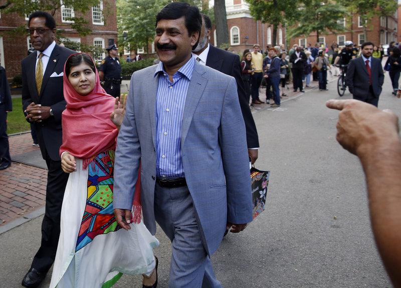 Malala Yousafzai waves to onlookers as she walks with her father, Ziauddin Yousafzai, right, and Director of the Harvard Foundation and Professor of Neurology at Harvard Medical School Dr. S. Allen Counter, through Harvard Yard after a news conference on the campus in Cambridge, Mass. on Friday, Sept. 27, 2013. The Pakistani teenager, an advocate for education for girls, survived a Taliban assassination attempt in 2012 on her way home from school. (AP Photo/Jessica Rinaldi)