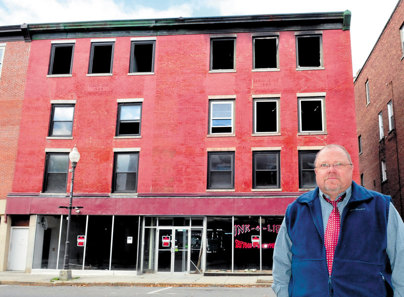 Building owner John Weeks stands in front of the apartment building on Main Street in Waterville that was destroyed by fire last May. Weeks says he plans to raze the structure and possibly build another at the site.