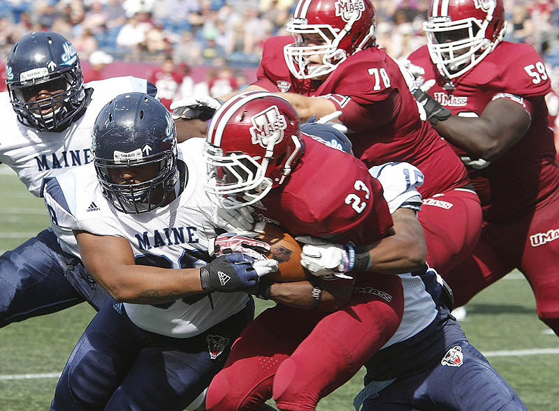Darius Green, left, and Jamal Clay bring down UMass running back Stacey Bedell, part of a UMaine defensive effort that limited the Minutemen to 265 yards.