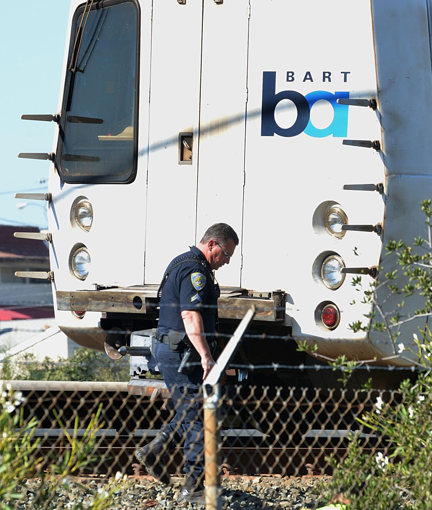 A BART police officer looks along the outside of a BART car that struck and killed two people along Jones Road in Walnut Creek, Calif., on Saturday, Oct. 19, 2013.