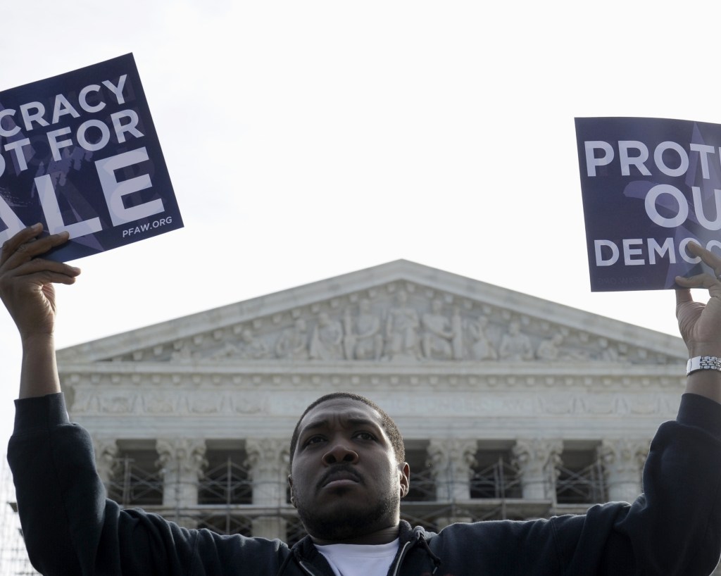 Cornell Woolridge of Windsor Mill, Md., protests Tuesday outside the Supreme Court in Washington as the court heard arguments on campaign finance.
