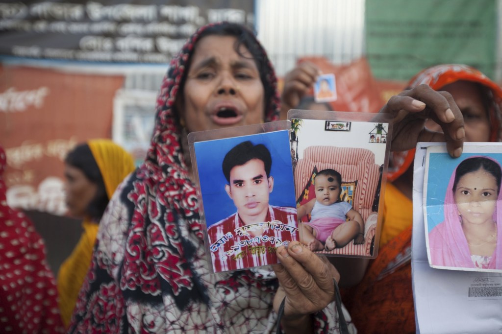 A woman displays photographs of loved ones on Thursday, the six-month anniversary of the Rana Plaza factory collapse.