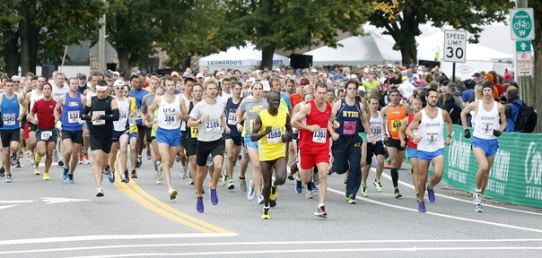 Runners take off at the start of Maine Marathon and half-marathon in Portland on Sunday. Rob Gomez, second from right, and Moninda Marube, in yellow at center, won the full and half-marathons respectively.