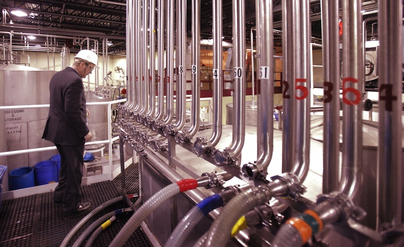 John Suczynski walks past a row of stainless steel pipes that transport alcohol to the bottling lines at White Rock Distilleries in Lewiston in 2011. 