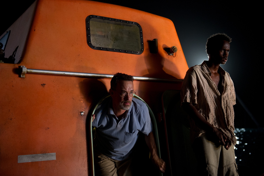 Tom Hanks, left, and Barkhad Abdirahman star in “Captain Phillips.” Below, Hanks deals with pirates on his ship.